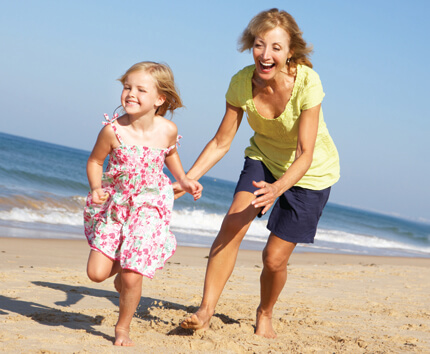 Woman playing with little girl on beach